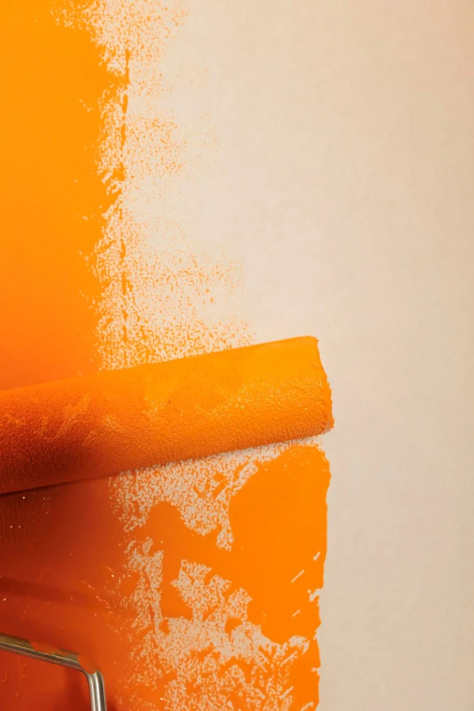 rolling-brush-with-orange-paint-renovate-redecorate-apartment-walls-changing-surface-color-with-dye-using-round-paintbrush-with-bristles-container-with-liquid-repaint-close-up